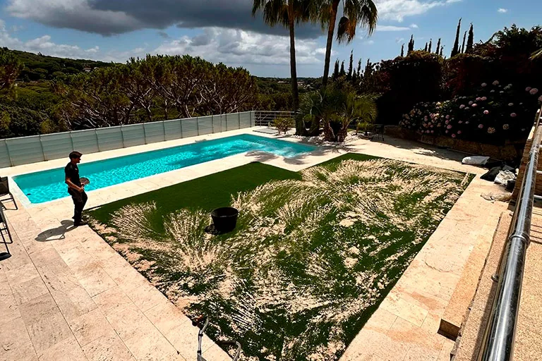 Jardín con césped artificial junto a una piscina tras la reforma