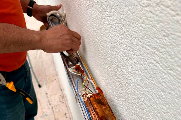 Electricista instalando canaleta para cableado en una pared