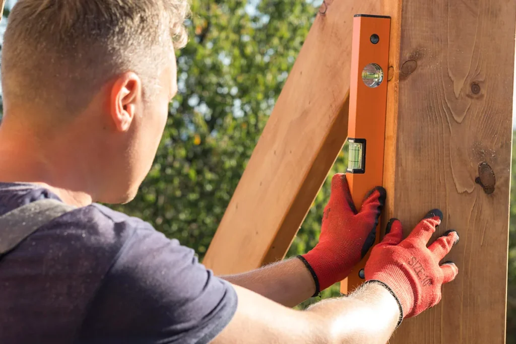 Manitas usando un nivel para instalar un listón de madera en exterior