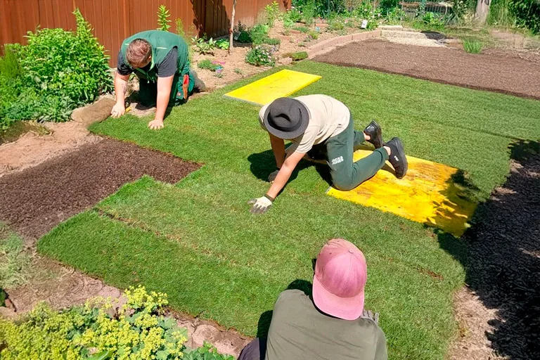 Operarios colocando césped natural en un jardín